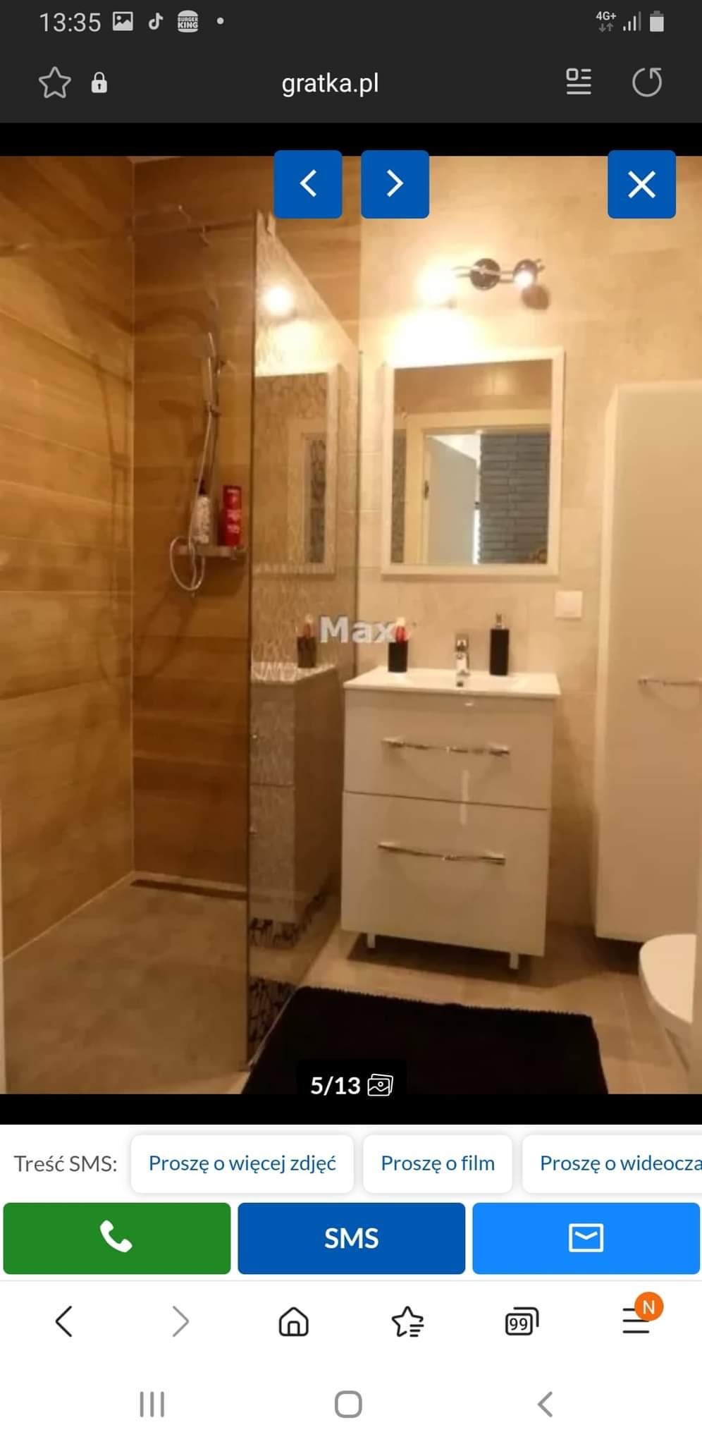 Nowoczesna łazienka z kabiną prysznicową typu walk-in, wykończona płytkami imitującymi drewno, biała szafka pod umywalką z dwoma szufladami i czarnym dywanikiem.