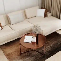 Jasny salon z beżową sofą, brązowymi i białymi poduszkami, okrągłym miedzianym stolikiem kawowym z książką i dekoracją kwiatową, oraz ciemnobrązowym dywanem na parkiecie.