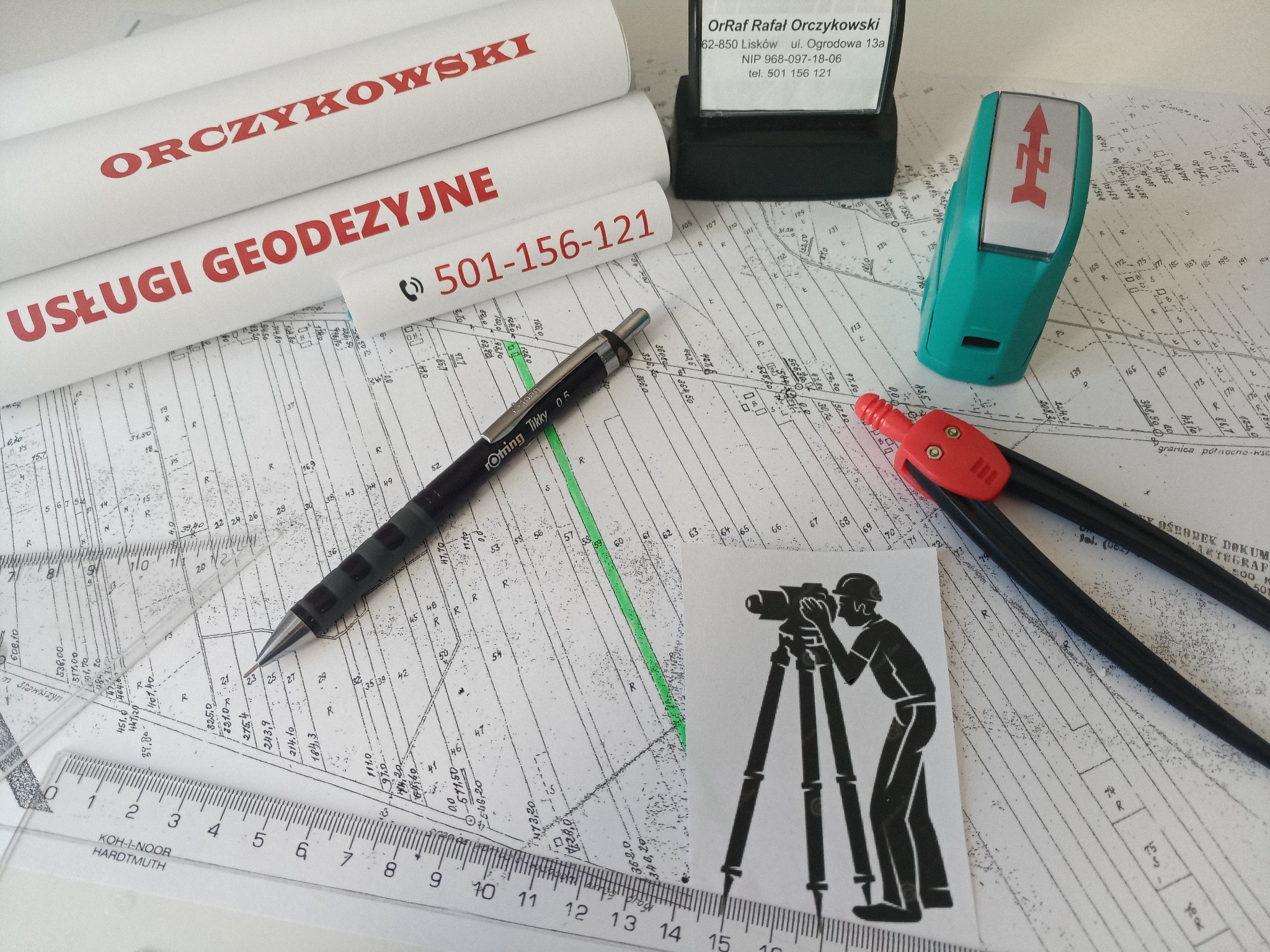 Szkic mapy geodezyjnej z naniesionymi pomiarami, otoczony narzędziami: ołówek automatyczny Rotring Tikky, cyrkiel z czerwoną końcówką, linijka, kątownik, pieczątka firmowa i rolki papieru...