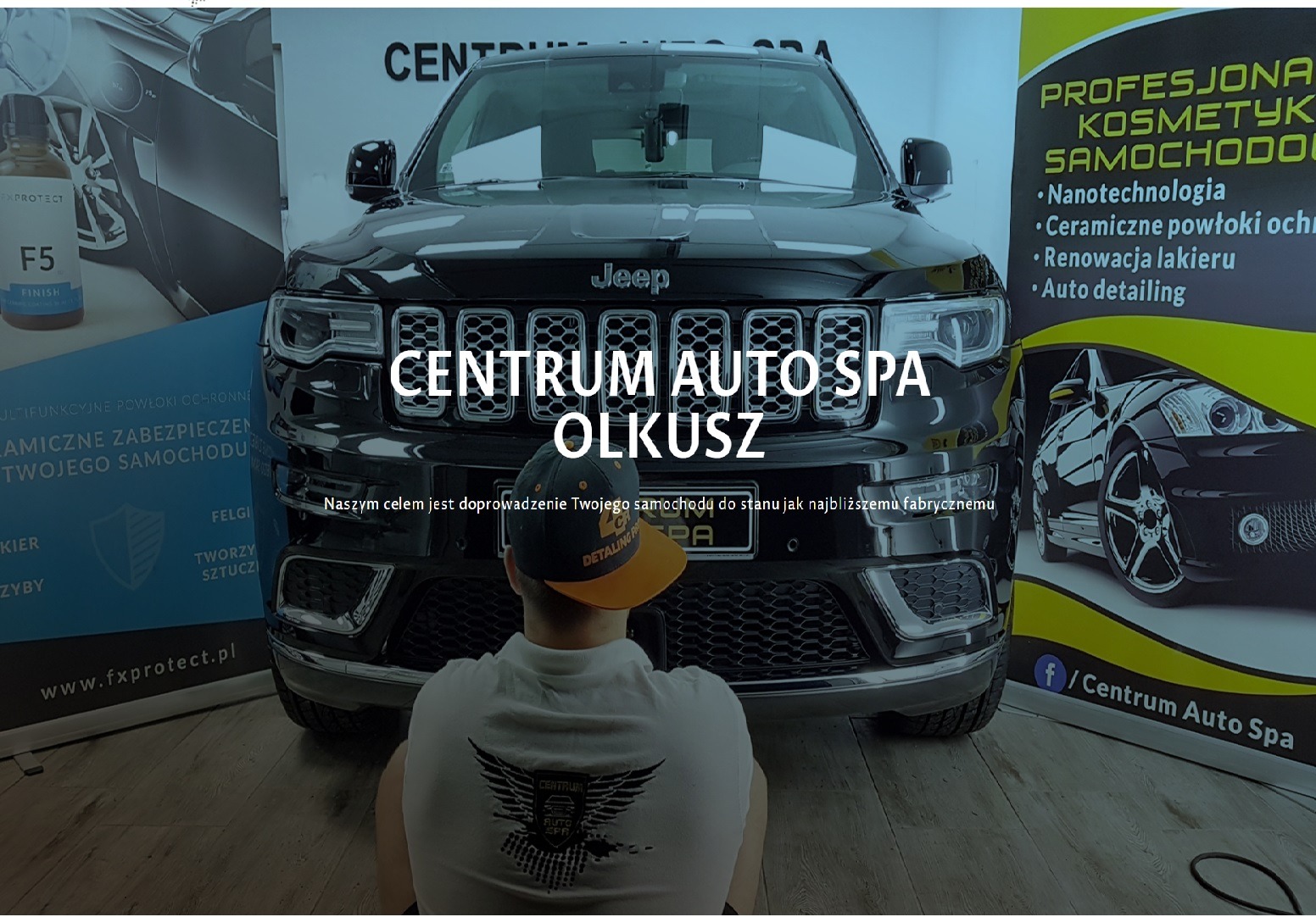 Czarny Jeep Grand Cherokee po detailingu, widok z przodu, w tle baner reklamowy Centrum Auto Spa Olkusz z informacjami o nanotechnologii, ceramicznych powłokach ochronnych, renowacji lakieru i auto...