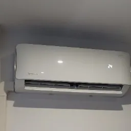 Biała jednostka klimatyzacji Rotenso zamontowana na ścianie w pomieszczeniu, widoczny wyświetlacz temperatury wskazujący 24 stopnie Celsjusza, z widoczną maskownicą instalacji elektrycznej.