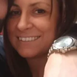 Portret uśmiechniętej kobiety z brązowymi włosami i zegarkiem na nadgarstku, obok fragmentu twarzy mężczyzny.