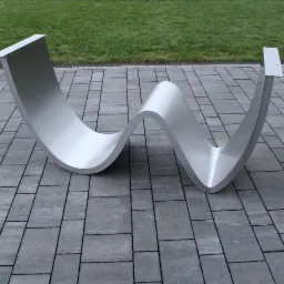 Falista, nowoczesna konstrukcja ze stali nierdzewnej na szarym bruku, z zielonym trawnikiem w tle. Element architektoniczny o gładkiej powierzchni i zaokrąglonych kształtach.