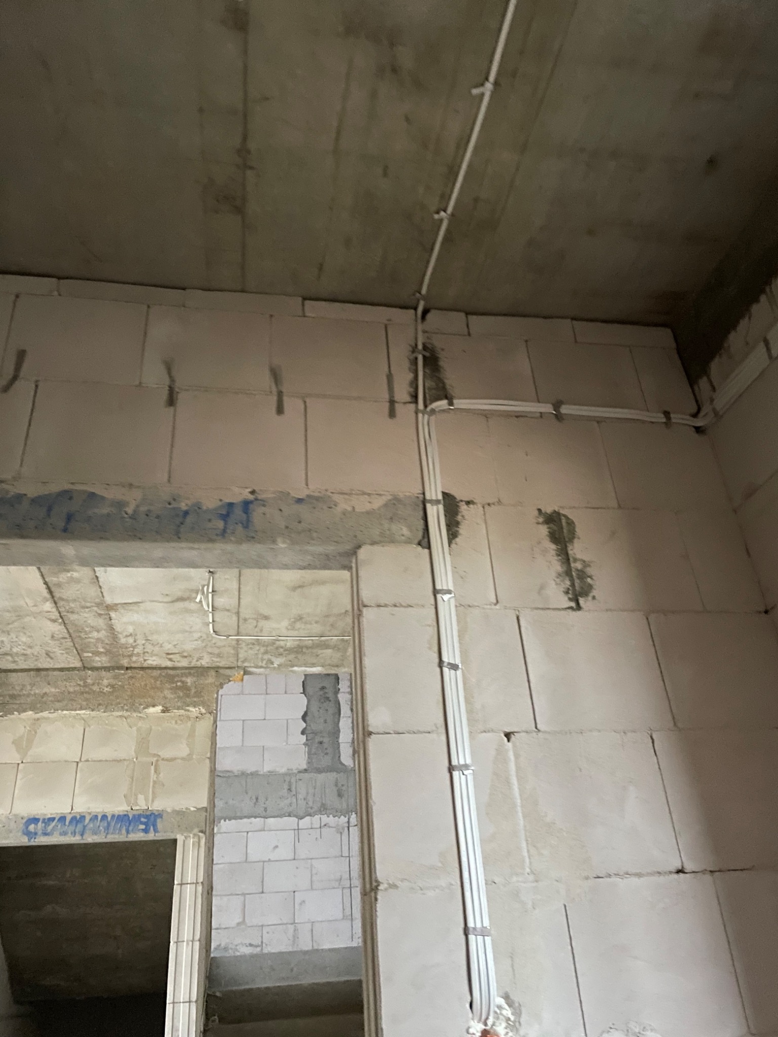 Wnętrze w trakcie budowy z widocznymi przewodami elektrycznymi poprowadzonymi po ścianach z betonu komórkowego i suficie, mocowanymi klamrami