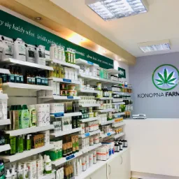 Wnętrze sklepu Konopna Farmacja: półki z kosmetykami i produktami konopnymi, logo z liściem konopi na ścianie za ladą, jasne oświetlenie.