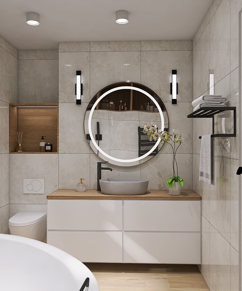 Nowoczesna łazienka z okrągłym lustrem z podświetleniem LED, szarą umywalką nablatową i białymi szafkami. Minimalistyczny design z drewnianym blatem i subtelnym oświetleniem.