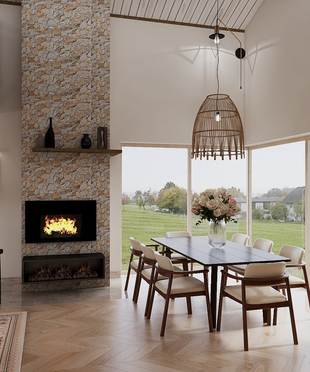 Jasne wnętrze jadalni z kamiennym kominkiem, drewnianym stołem i krzesłami. Wazon z kwiatami na stole. Duże okna z widokiem na zieleń. Wnętrze w neutralnych barwach.