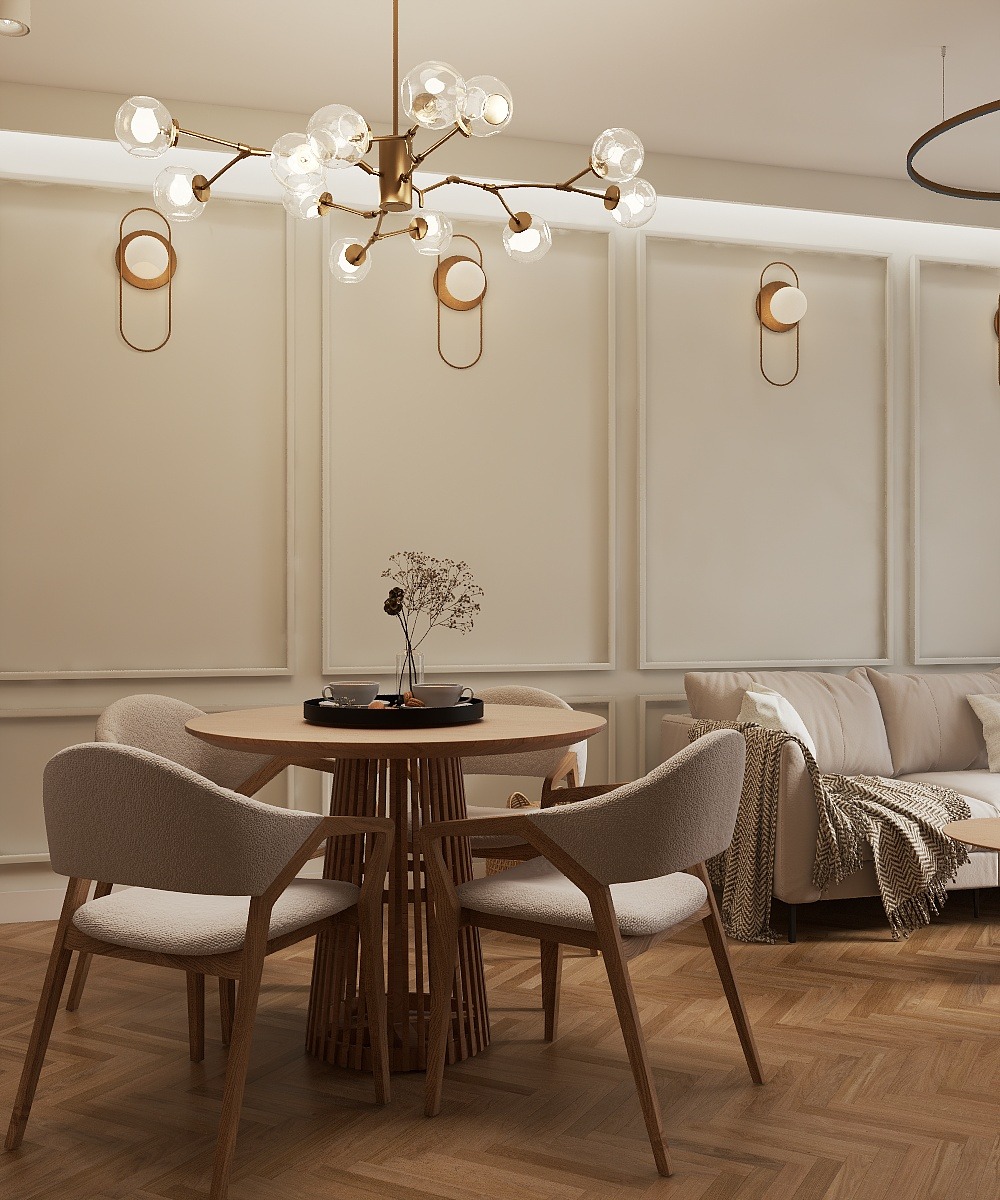 Jasne wnętrze jadalni z okrągłym stołem, czterema krzesłami i designerską lampą sufitową. Parkiet w jodełkę, stonowana kolorystyka, minimalistyczne dekoracje.