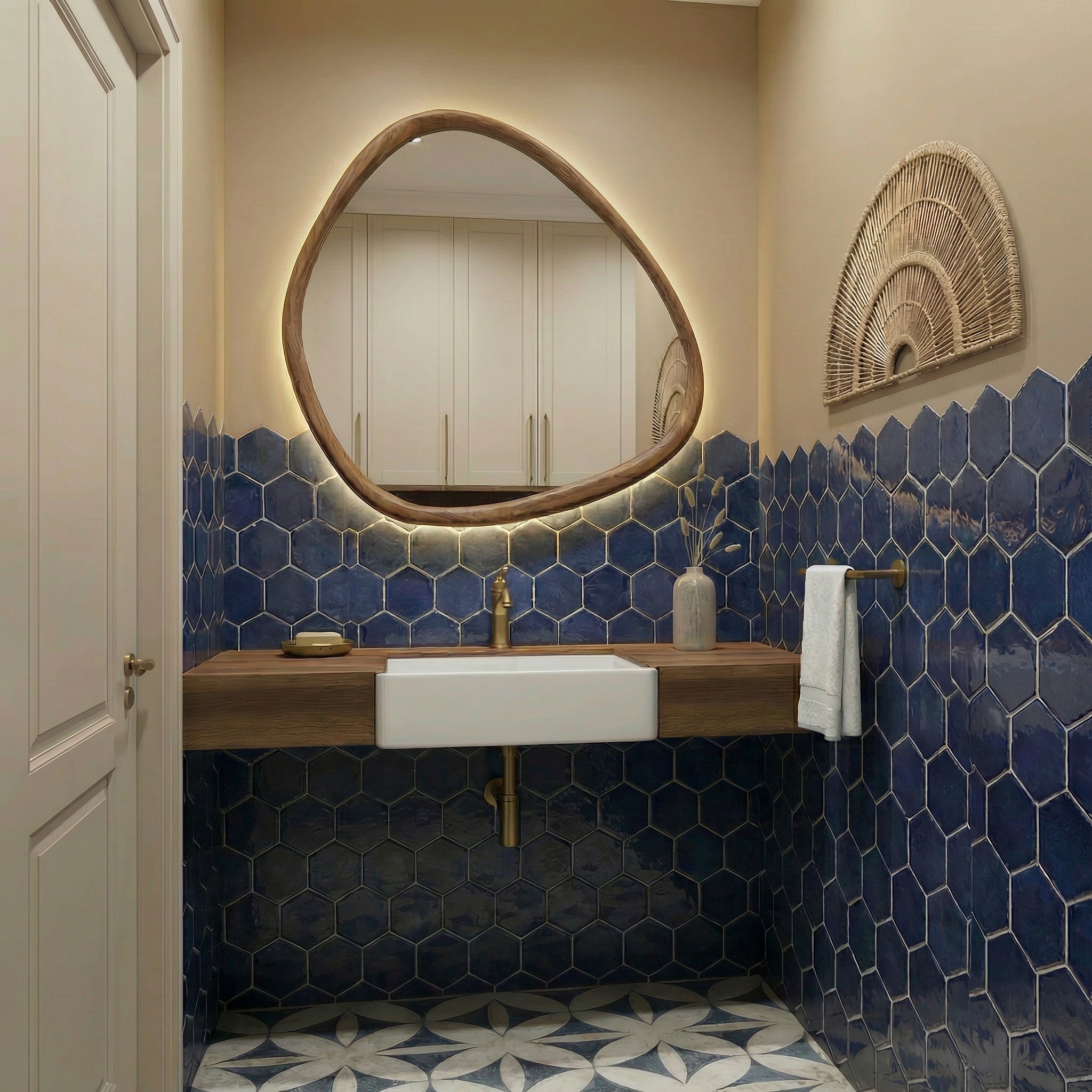 Nowoczesna łazienka z umywalką nablatową, lustrem o nieregularnym kształcie z podświetleniem LED i niebieskimi heksagonalnymi płytkami. Wystrój uzupełnia rattanowa dekoracja.