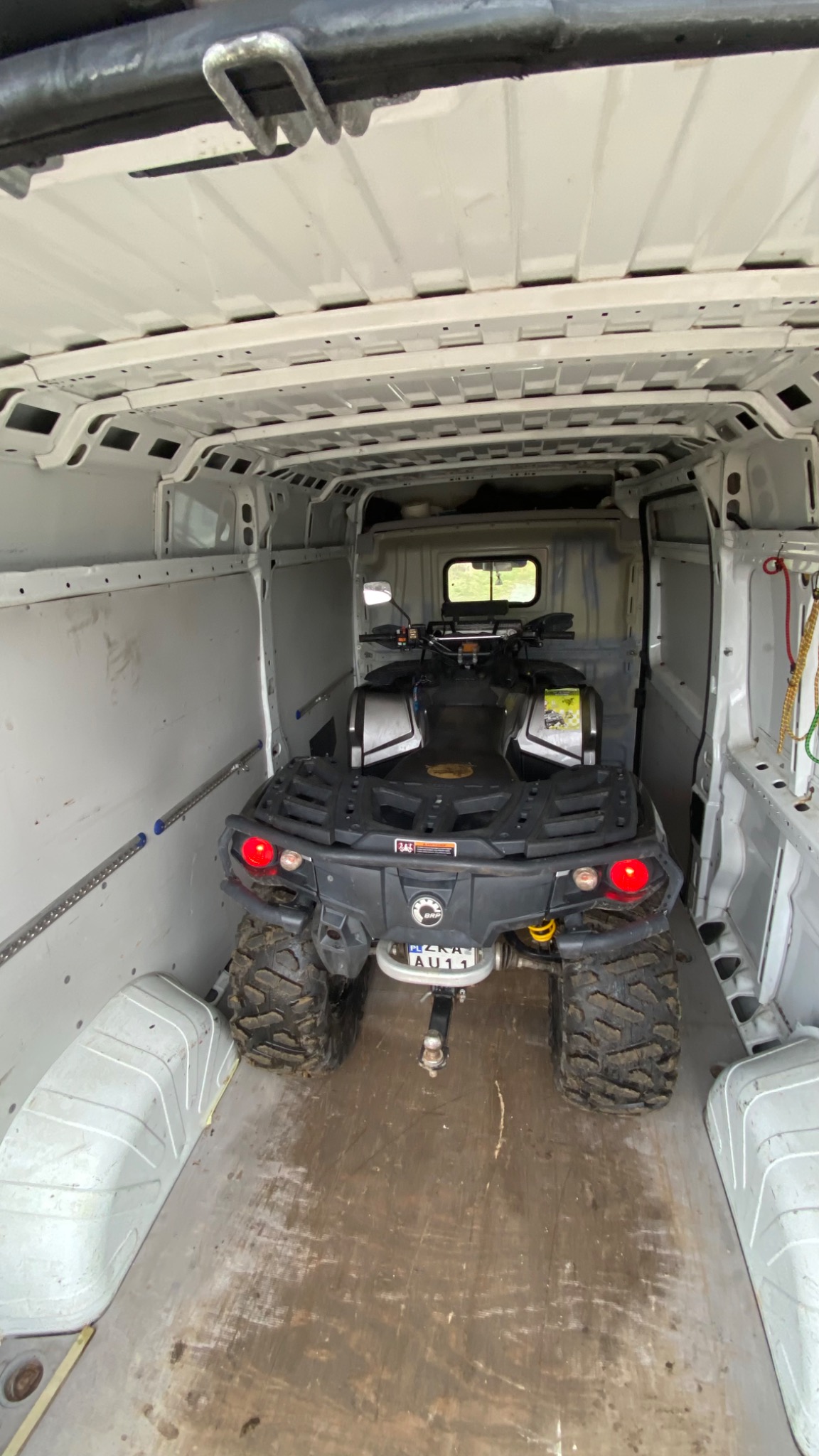 Czarny quad marki BRP z widoczną tablicą rejestracyjną PL ZKA AU11, zabezpieczony wewnątrz białej furgonetki transportowej z systemem mocowań na ścianach.