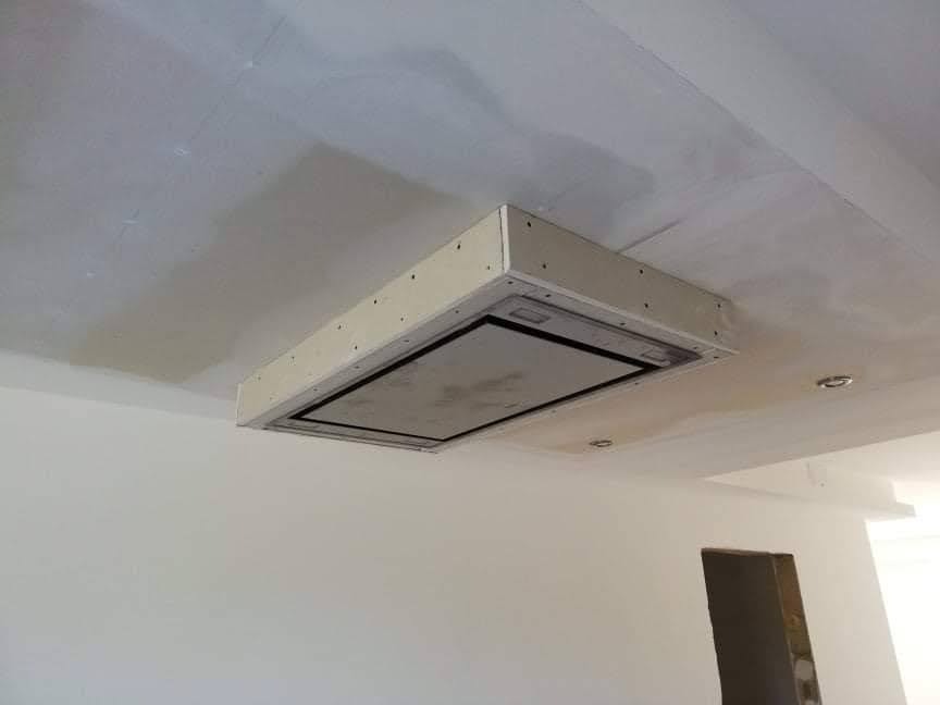 Niedokończona obudowa sufitowa z płyty gipsowo-kartonowej wokół okapu kuchennego, widoczne ślady szpachlowania na suficie, surowy stan.