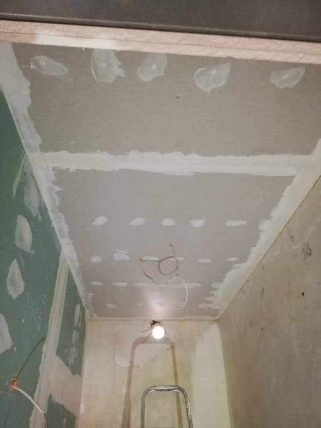 Sufit w trakcie szpachlowania, widoczne kable oświetleniowe i drabina.