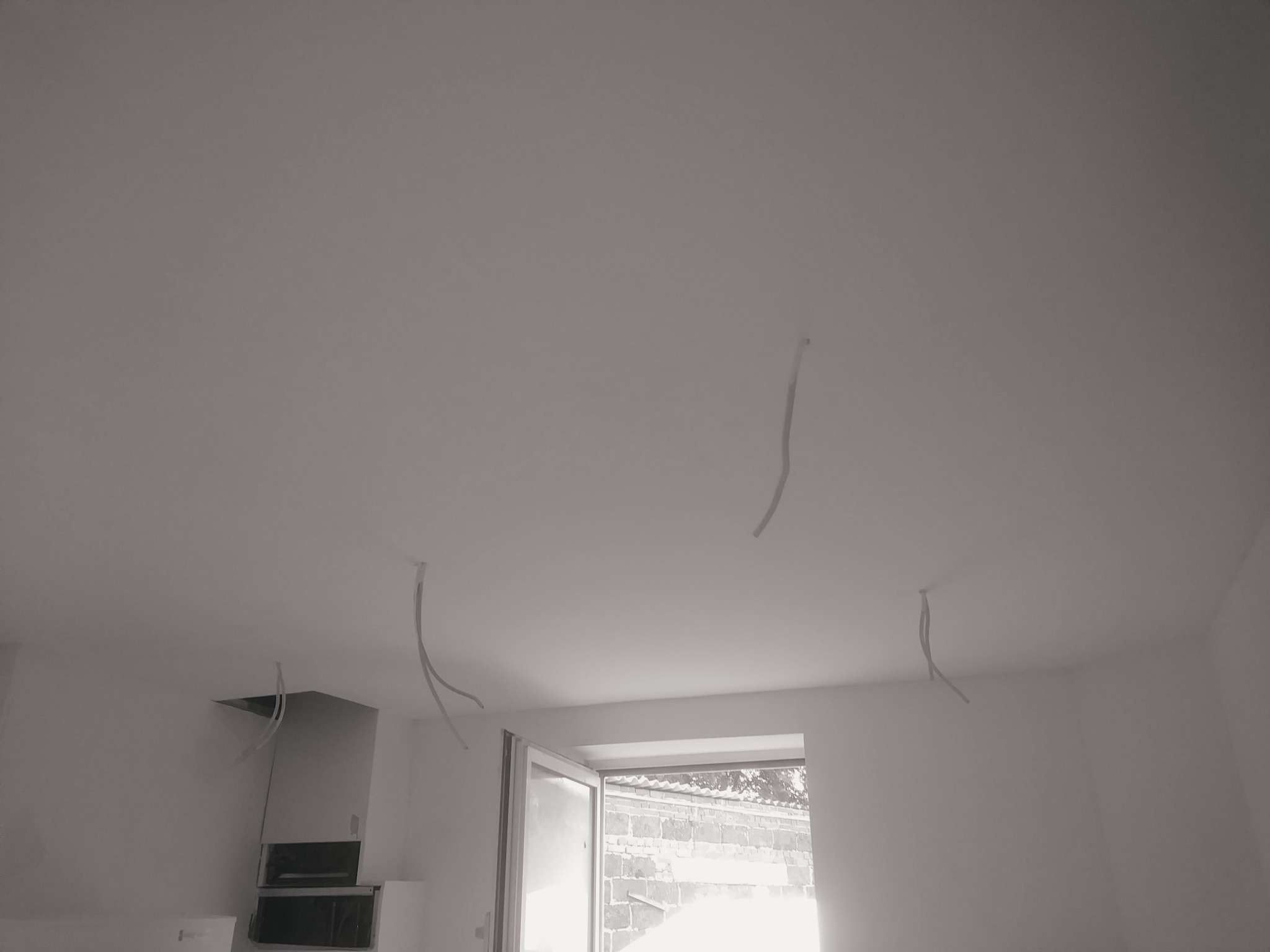 Przygotowanie do remontu w Oberhausen: białe ściany, sufit z wystającymi przewodami elektrycznymi, otwarte okno w tle.