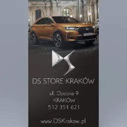 Roll-up reklamowy DS Store Kraków z brązowym samochodem DS 7 Crossback na tle budynku z kolumnami.