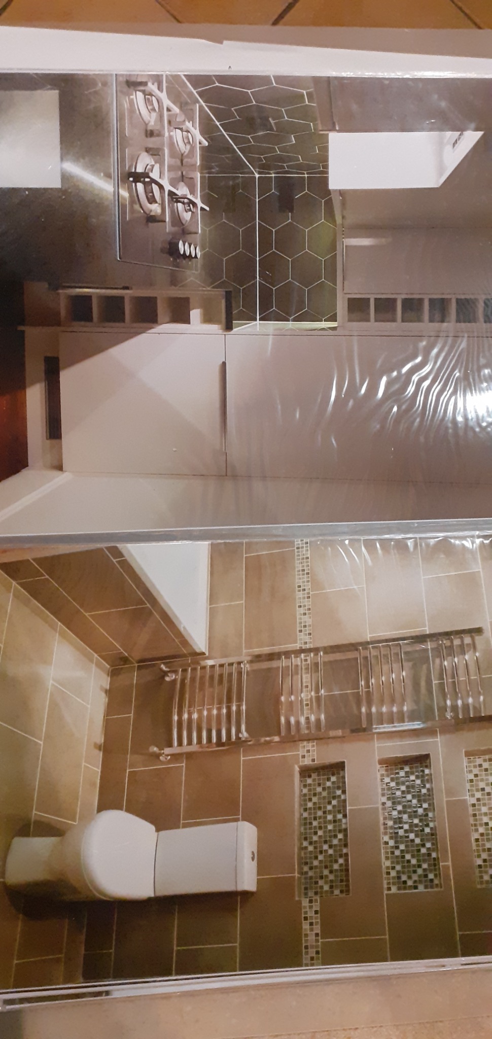 Wnętrze łazienki z beżowymi płytkami, prysznicem ze szklaną kabiną, toaletą i półkami wnękowymi z mozaiką.