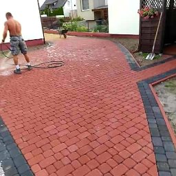 Fabian Patalon - Czerwona kostka brukowa z czarnym obramowaniem, czyszczona myjką ciśnieniową przez mężczyznę bez koszulki na tle domu jednorodzinnego.