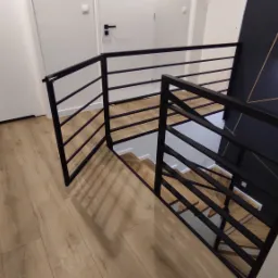 Nowoczesna, czarna balustrada metalowa z poziomymi szczeblami na schodach w jasnym wnętrzu, widok z g&oacute;ry, podłoga imitująca drewno.