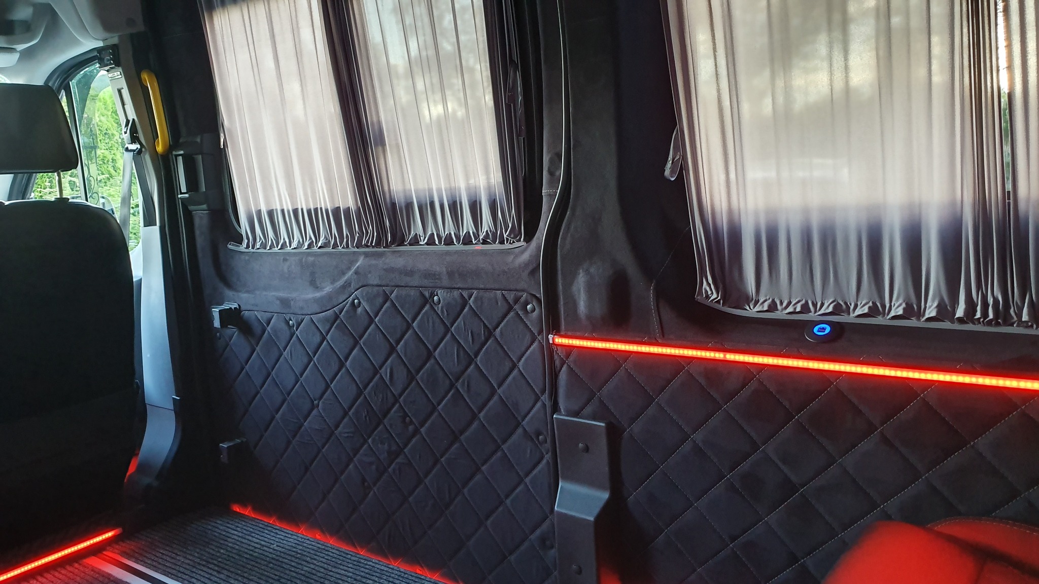 Wnętrze luksusowo wykończonego busa w Garwolinie: pikowana tapicerka, zasłony w oknach i nastrojowe oświetlenie LED.