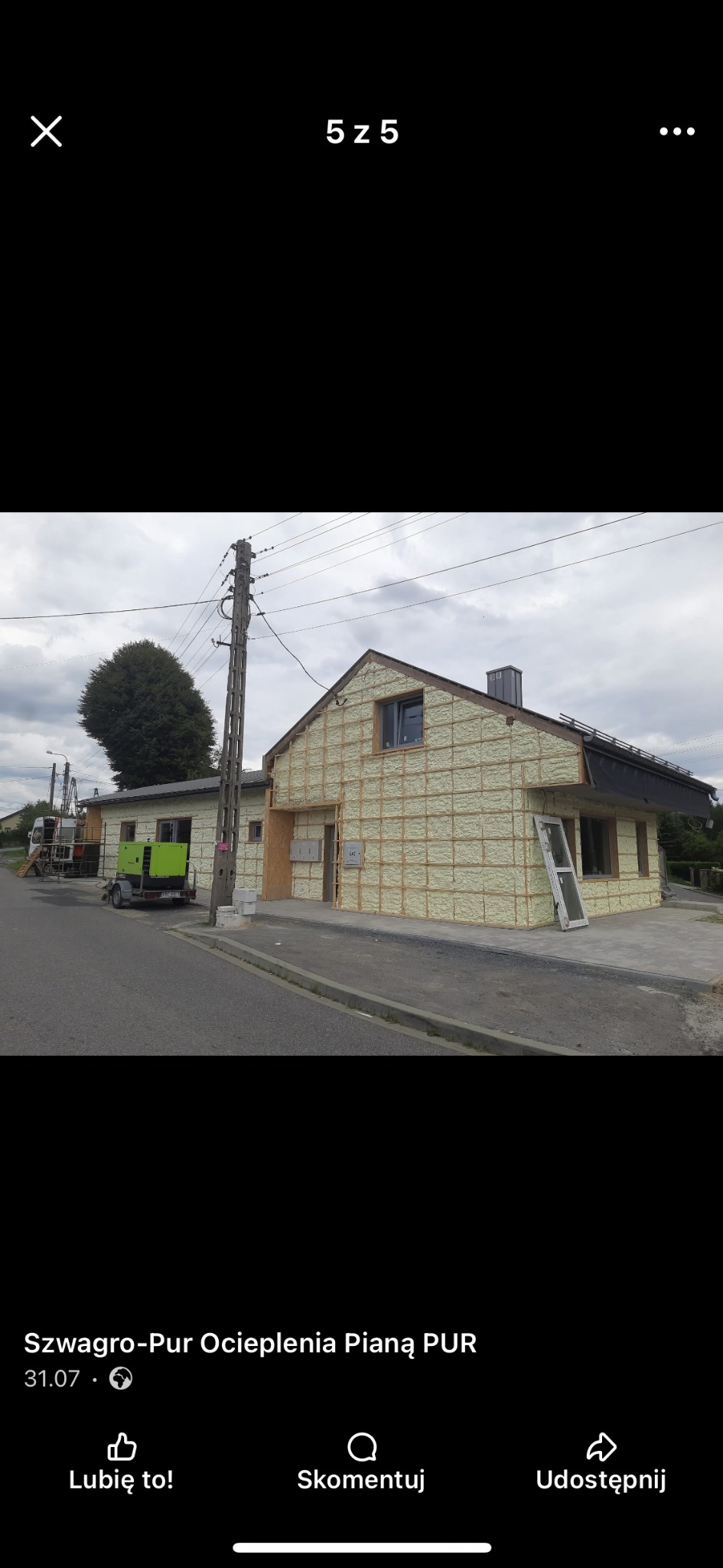 Budynek w trakcie ocieplania. Widoczna szkieletowa konstrukcja i wypełnienie pianką. Na pierwszym planie okno oparte o ścianę, w tle agregat prądotwórczy.