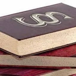 Stos trzech grubych, oprawionych książek z paragrafem na wierzchniej, ciemnobrązowej okładce, ułożonych na białym tle.