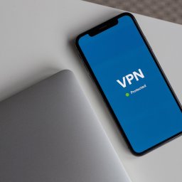 VPNmaniak - Smartfon z ekranem wyświetlającym napis VPN Protected leżący obok laptopa na białym stole w Poznaniu.
