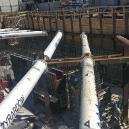 MALMAC Sp. z o.o - Głęboki wykop zabezpieczony szalunkiem stalowym i rurami Żyrardów, widoczne zbrojenie i pracownicy w kaskach.