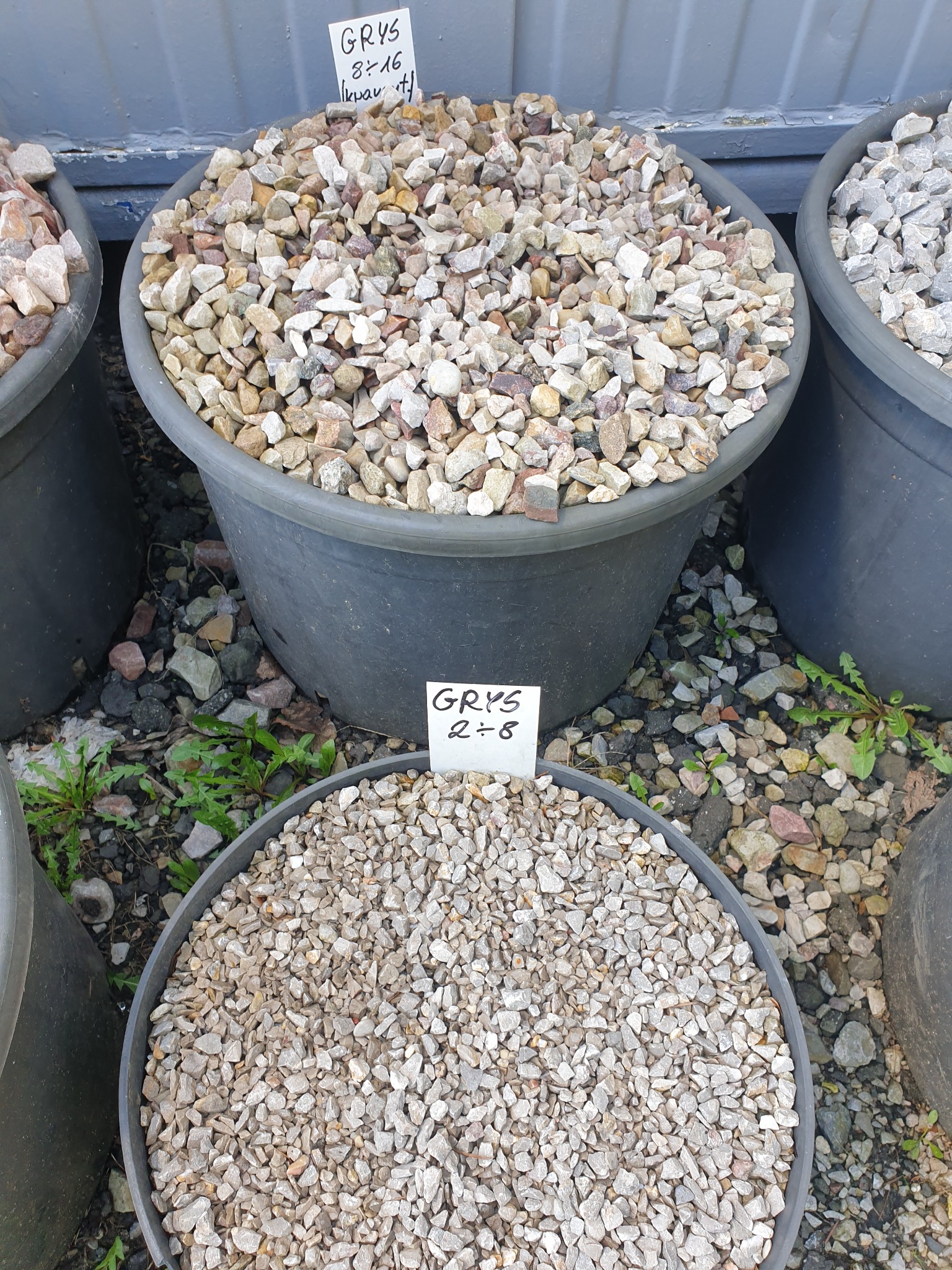 Grys o frakcji 8-16 i 2-8 w czarnych pojemnikach, oferowany w Piasecznie, z widocznymi etykietami informacyjnymi.