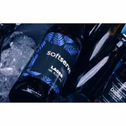 Butelki piwa lager Softserve i Doctor w wiaderku z lodem, widoczne etykiety z informacjami o składzie i producencie.