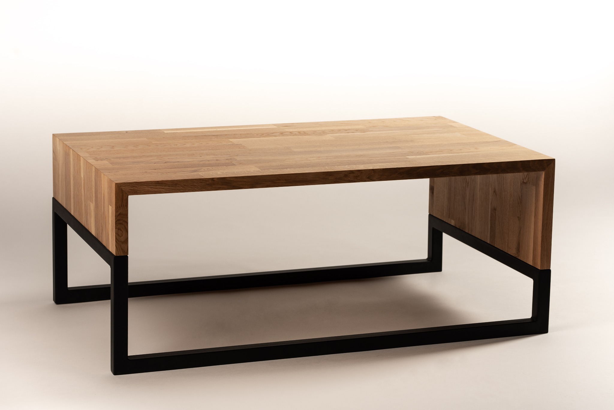 Stół kawowy z blatem z klejonego drewna i czarną, metalową podstawą w stylu industrialnym, na jasnym tle.