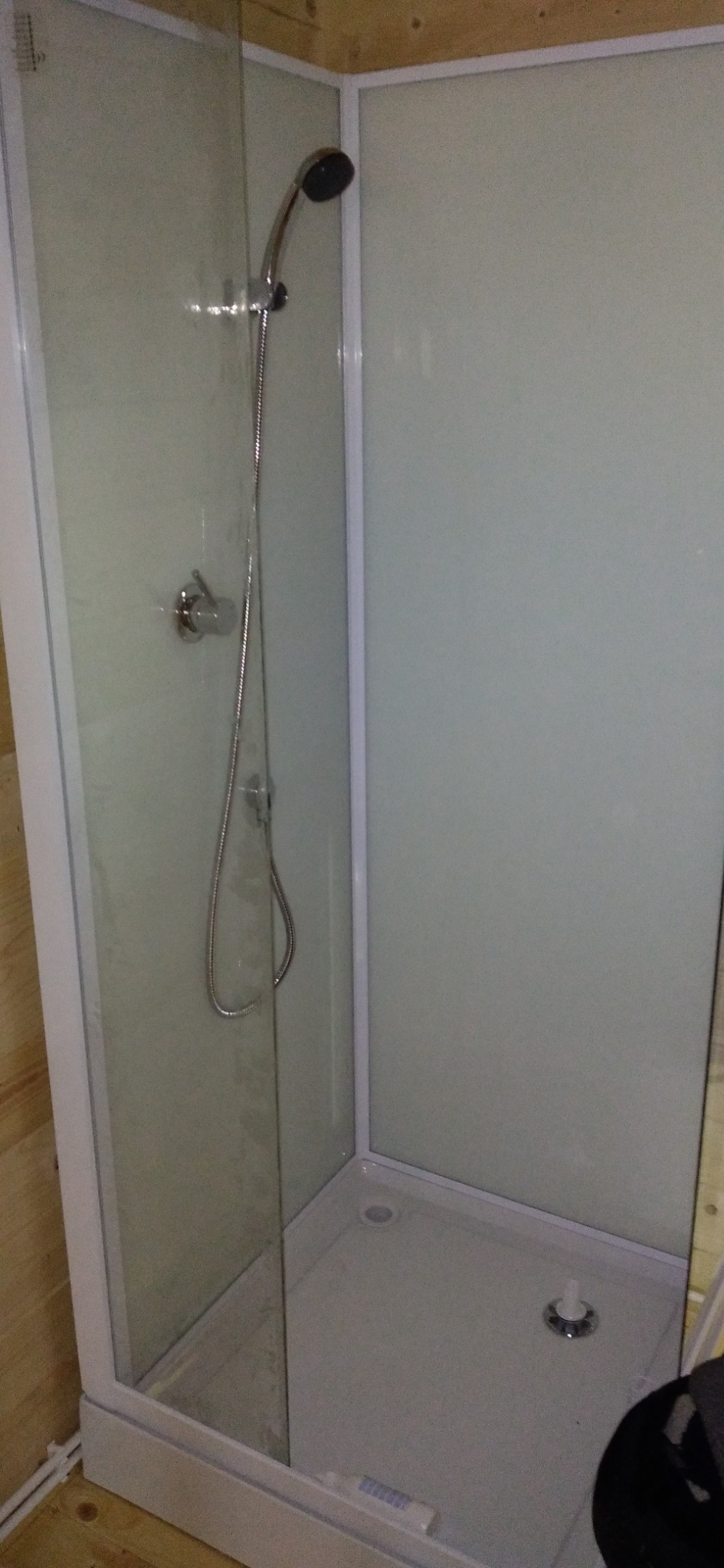 Kabina prysznicowa z chromowaną baterią i słuchawką, zamontowana w pomieszczeniu wykończonym drewnem.