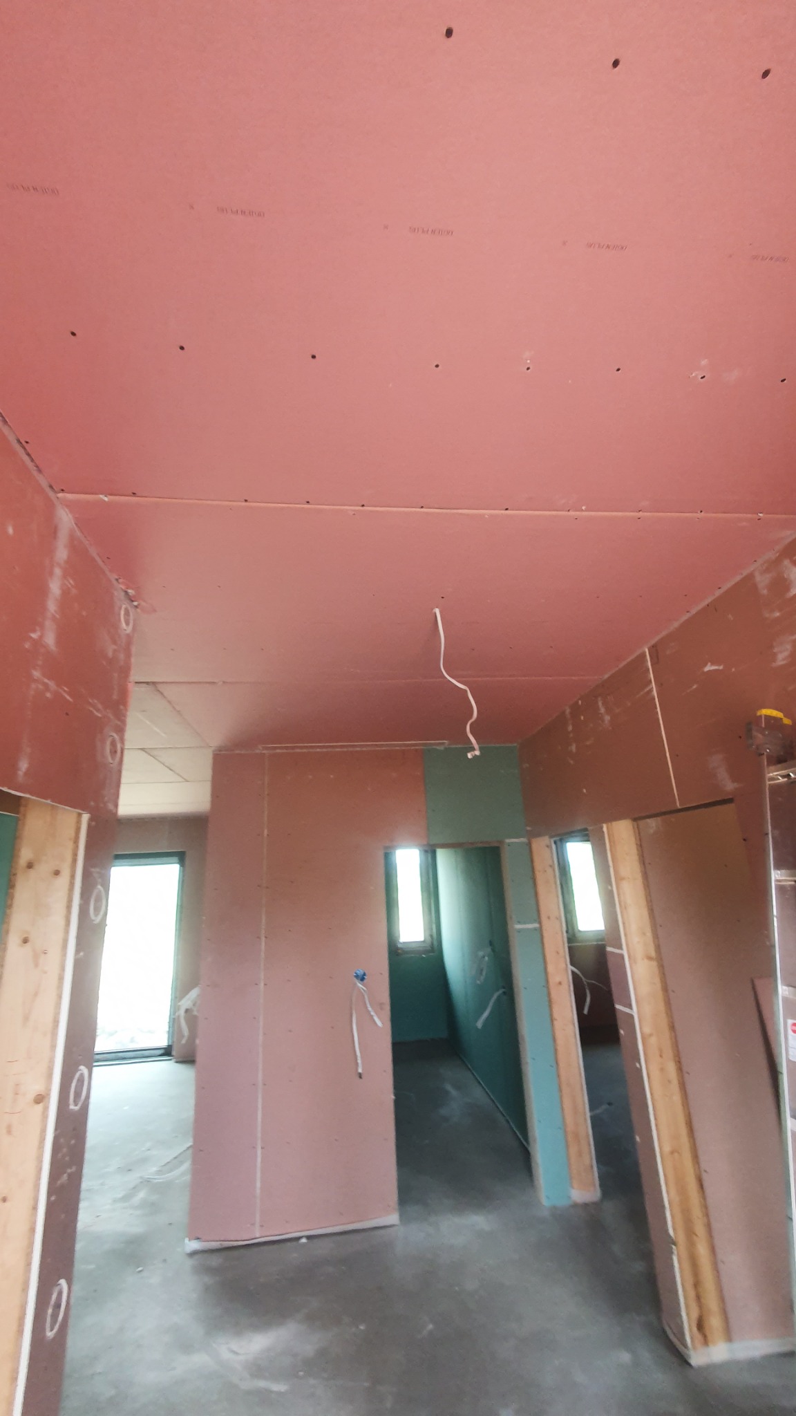 Wnętrze w trakcie montażu okładzin ściennych i sufitowych z płyt gipsowo-kartonowych, widoczne elementy konstrukcyjne ścian działowych z drewna, przewody elektryczne wystające ze ściany, surowy...