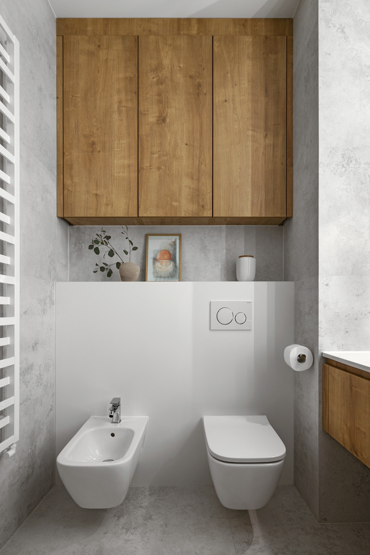 Nowoczesna łazienka z wiszącą toaletą i bidetem, szara płytka imitująca beton, drewniane szafki wiszące i grzejnik drabinkowy