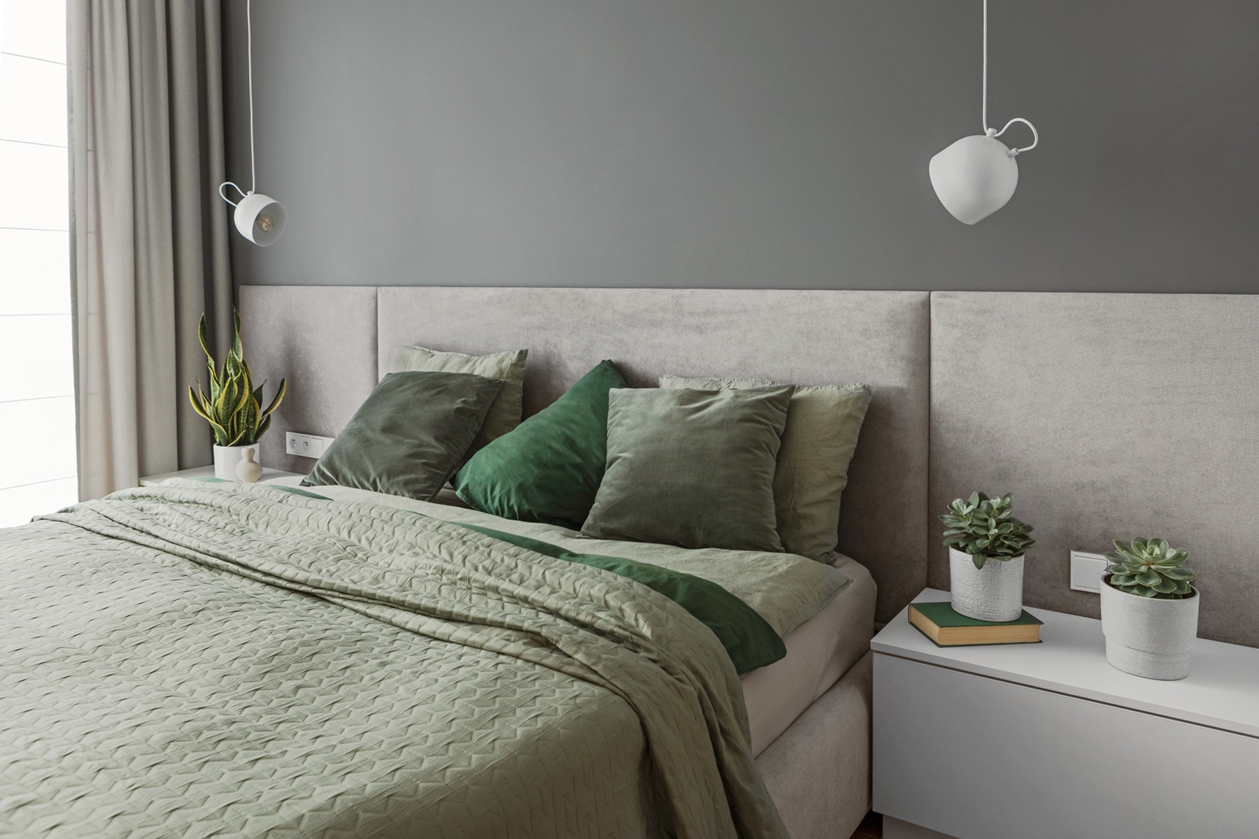 Sypialnia w odcieniach szarości i zieleni z pikowaną narzutą, welurowymi poduszkami i lampkami nocnymi w kształcie kuli.