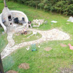 Mariusz Urbanski - Budowa kamiennego tarasu i ścieżki w ogrodzie z widocznym paleniskiem i dwoma pracownikami układającymi kamienie