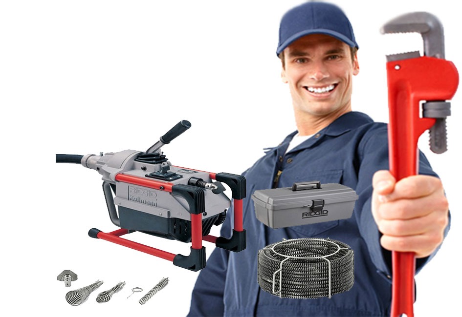 Uśmiechnięty hydraulik w niebieskim uniformie prezentuje zestaw narzędzi do udrażniania rur: maszynę Ridgid Kollmann, sprężynę w metalowym koszu, wymienne końcówki i skrzynkę narzędziową, trzymając...