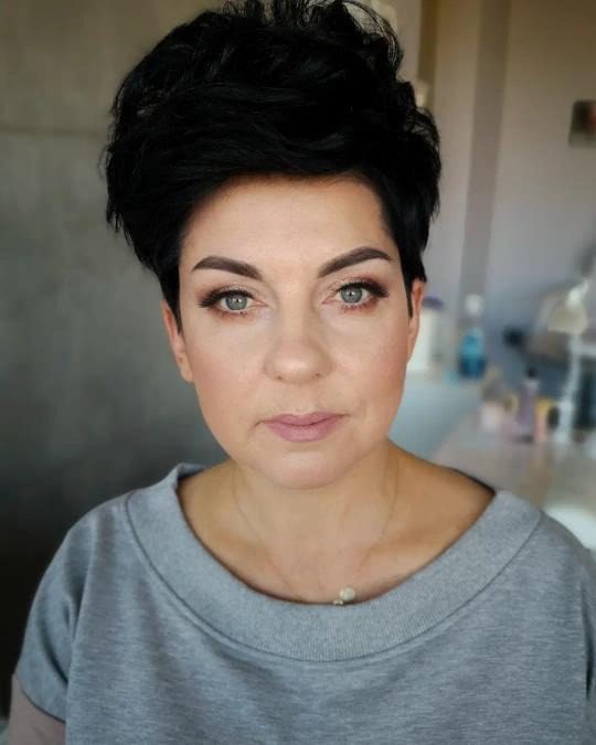 Portret kobiety z krótkimi, czarnymi włosami i subtelnym, dziennym makijażem, z delikatnie podkreślonymi oczami i ustami w odcieniu nude.