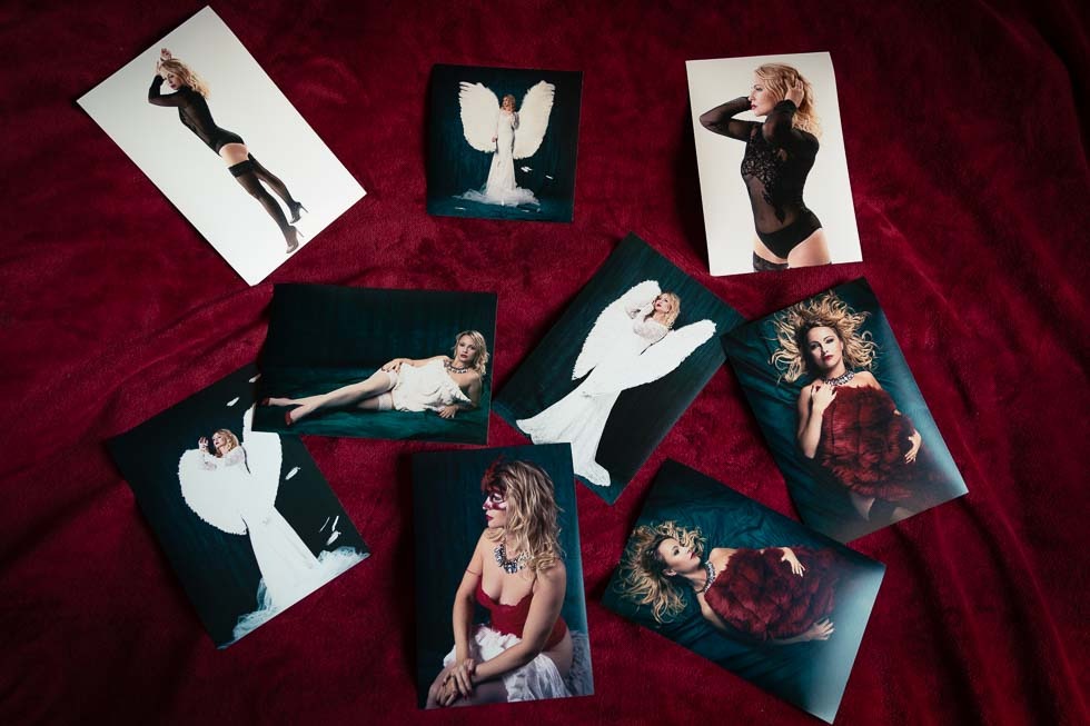 Rozłożone na czerwonym aksamitnym tle wydrukowane fotografie modelek w różnych pozach, strojach i stylizacjach, niektóre z anielskimi skrzydłami, inne w bieliźnie.