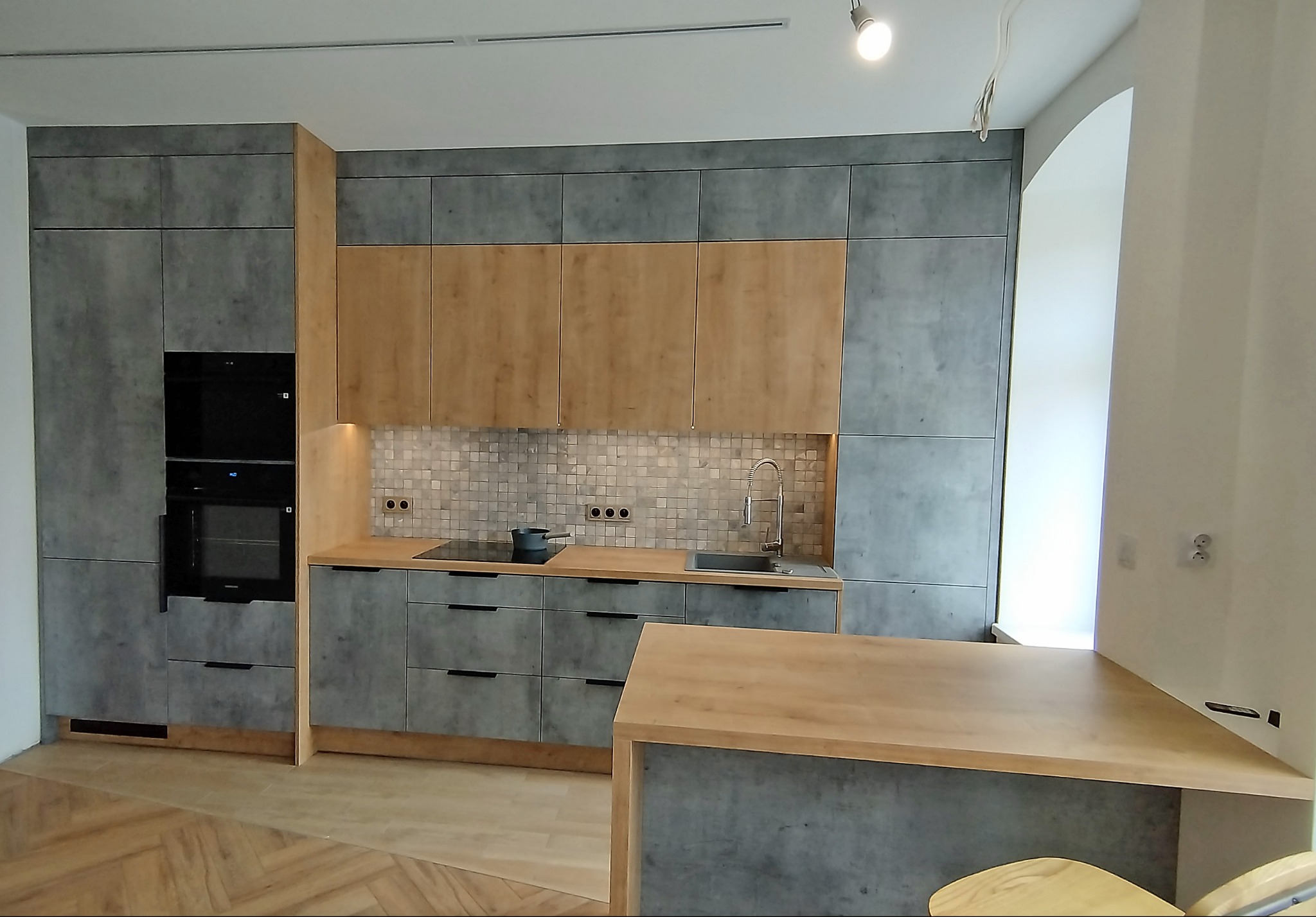 Kaskadowy układ zabudowy kuchennej - materiały to płyta laminowana Dąb Hamilton i Beton