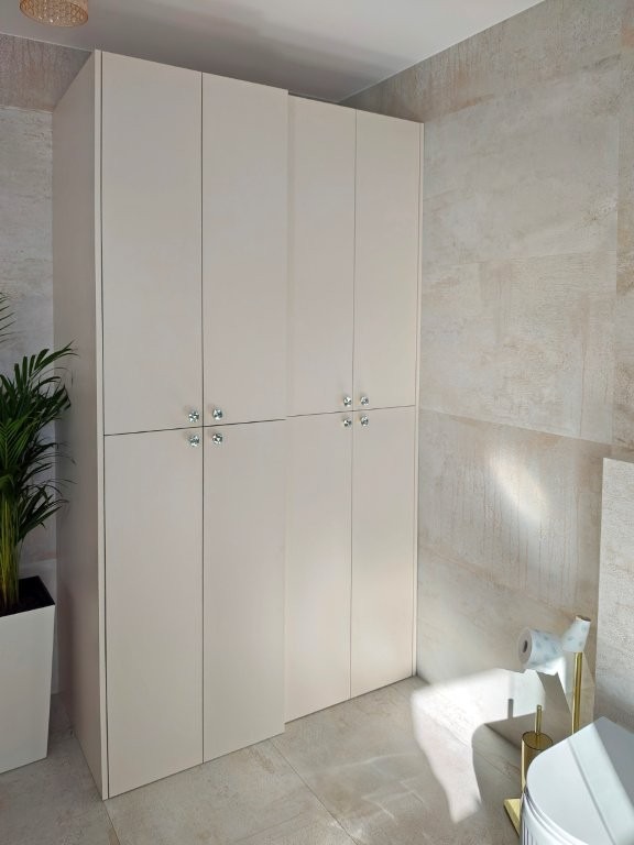 Zabudowa łazienki - szafa skrywa pralkę i suszarkę.