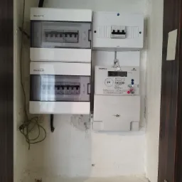 Rozdzielnia elektryczna z dwoma modułami zabezpieczeń Elektro-Plast i licznikiem energii elektrycznej Norax 3 Apator zamontowana wewnątrz wnęki z widocznymi przewodami. Obok widoczny fragment...