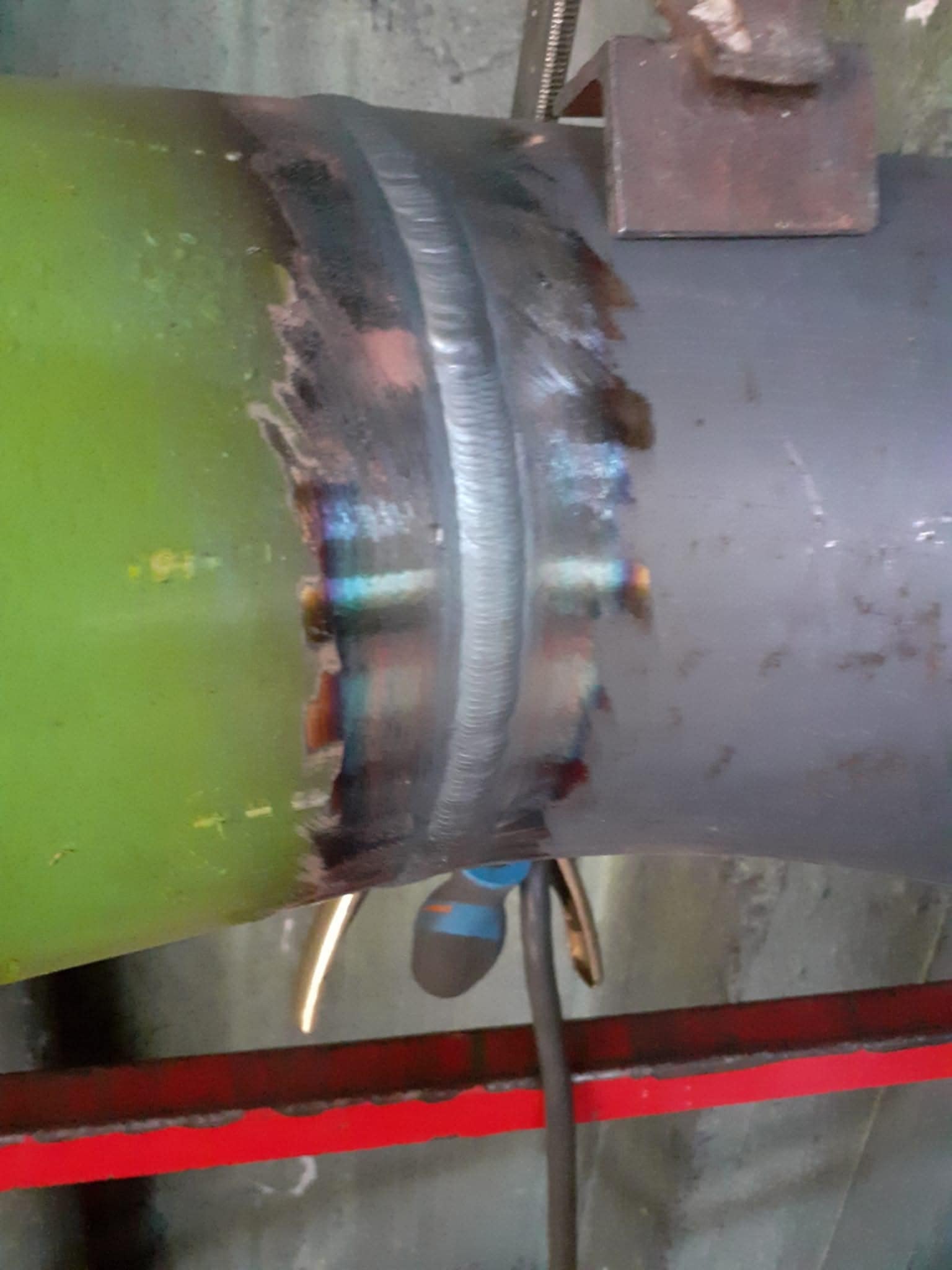 Spoina na rurze łączącej elementy instalacji, widoczne ślady obróbki termicznej i przebarwienia metalu. Zastosowano uchwyt stabilizujący podczas spawania.