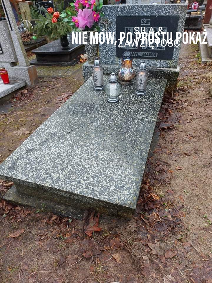 Granitowy pomnik z napisem 'AVE MARIA' i czterema lampionami, otoczony ziemią i opadłymi liśćmi na cmentarzu.