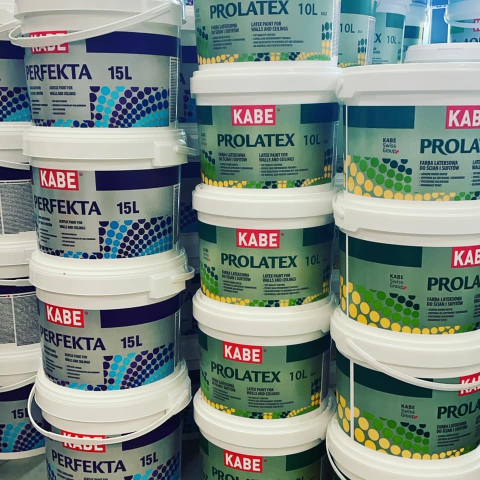 Pionowy stos wiader z farbą lateksową KABE PERFEKTA i PROLATEX w sklepie, widoczne etykiety z informacjami o produkcie i pojemności.