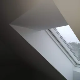 Wnętrze poddasza z oknem dachowym, widok na zewnątrz z kroplami deszczu na szybie, świeżo pomalowane ściany w odcieniach bieli i szarości.