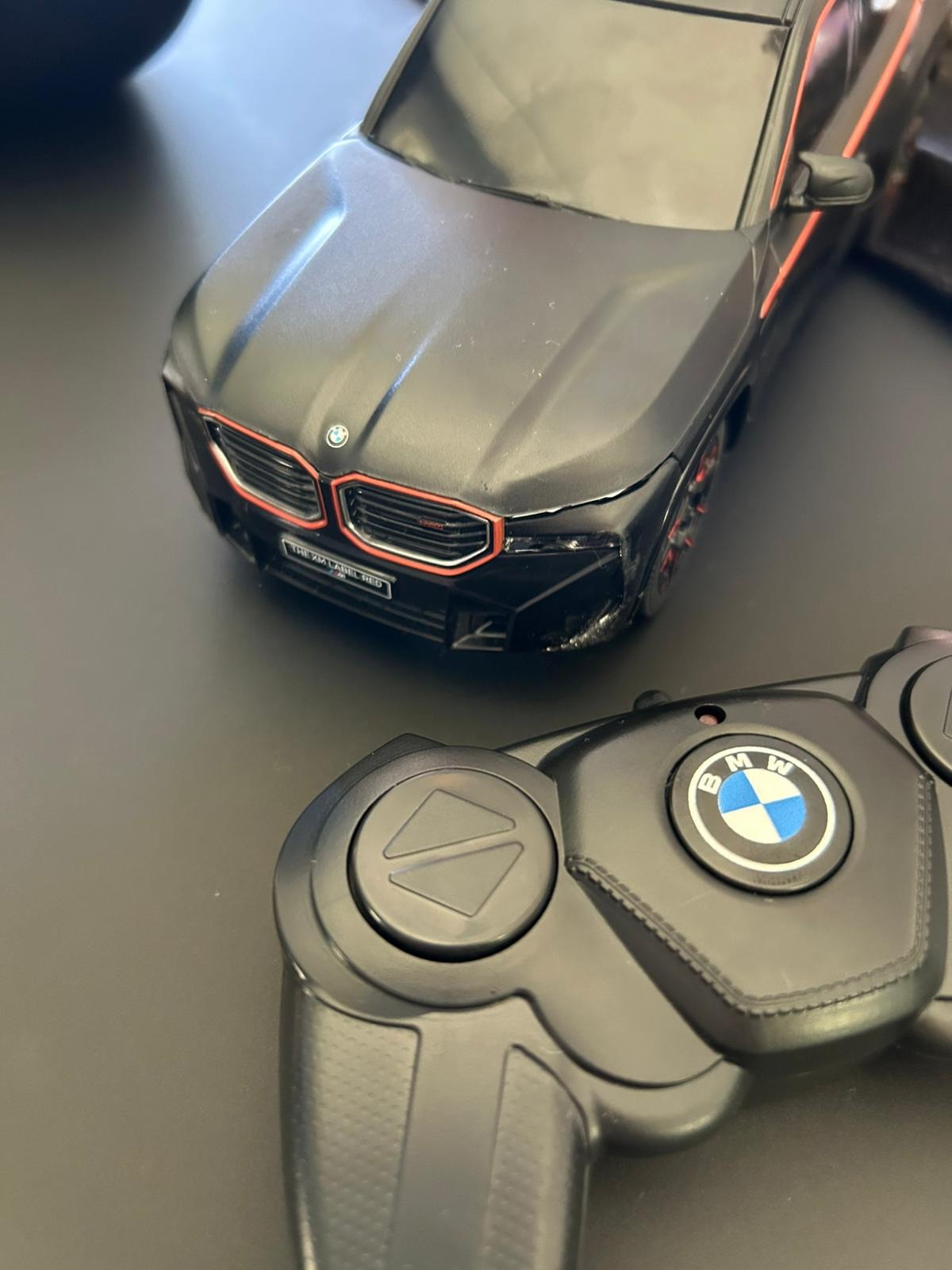 Model auta BMW XM Label Red z pilotem. Detaliczne odwzorowanie, matowa czerń z pomarańczowymi akcentami. Pilot z logo BMW.
