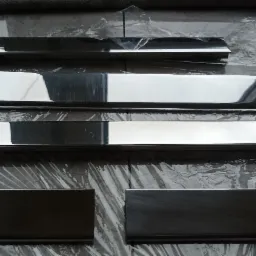 Polerowane, prostokątne metalowe elementy o różnej grubości, ułożone na folii ochronnej, prawdopodobnie przygotowane do montażu.