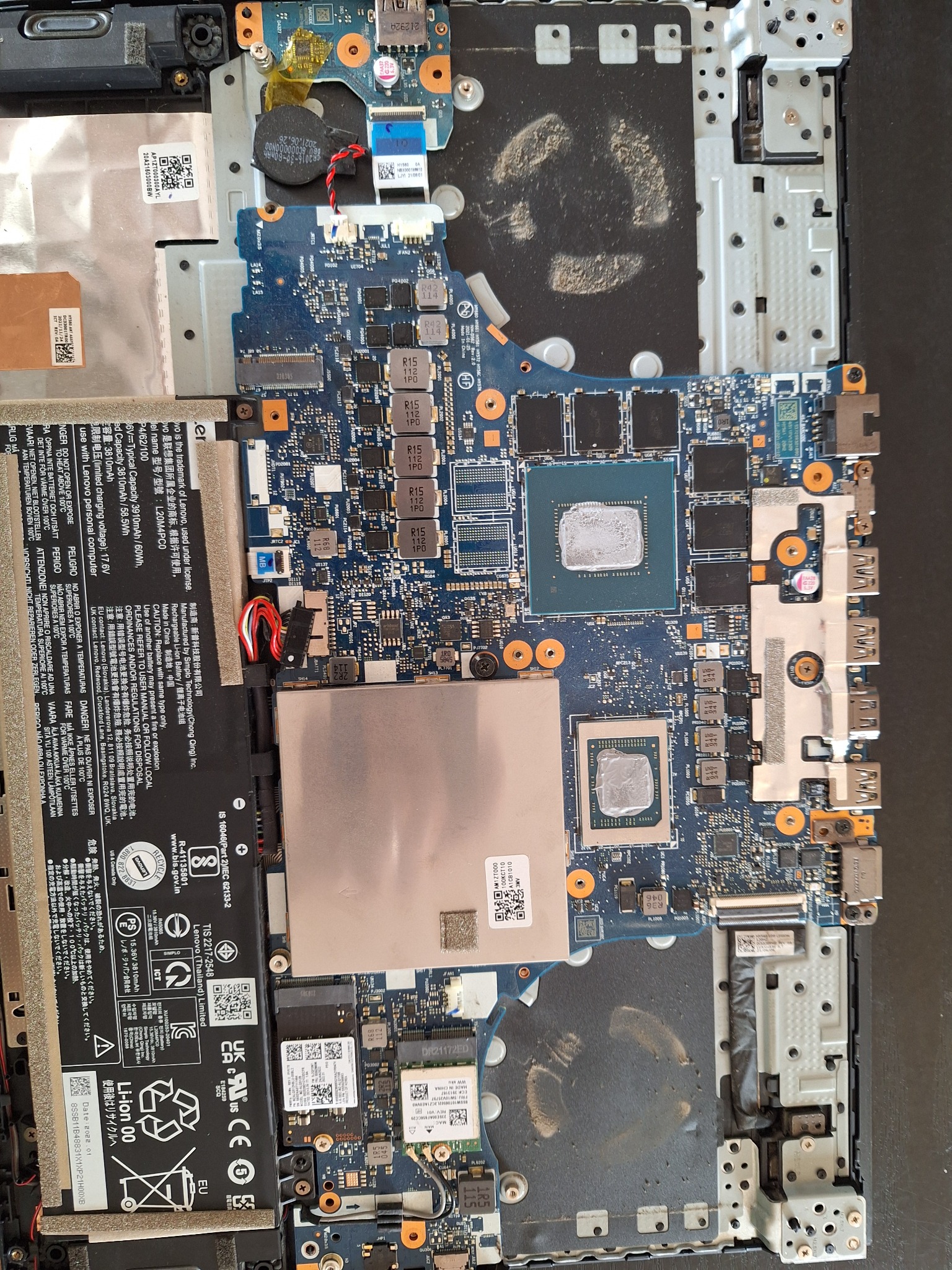 Wnętrze laptopa Lenovo Legion z widoczną płytą główną, baterią i elementami chłodzenia po demontażu obudowy. Widoczne ślady kurzu i pasty termoprzewodzącej na procesorach.
