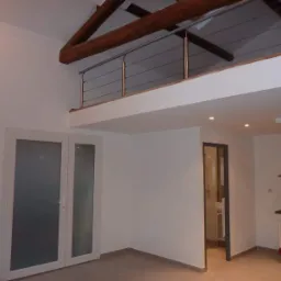 Jasne wnętrze z antresolą i drewnianymi belkami stropowymi, widok na kuchnię z czerwonymi akcentami i łazienkę z kabiną prysznicową.