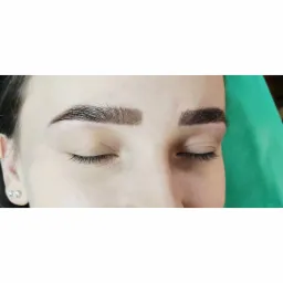 Zbliżenie na brwi po zabiegu laminacji i henny, widoczne włoski pokryte preparatem, sk&oacute;ra wok&oacute;ł czysta, zamknięte oczy modelki.