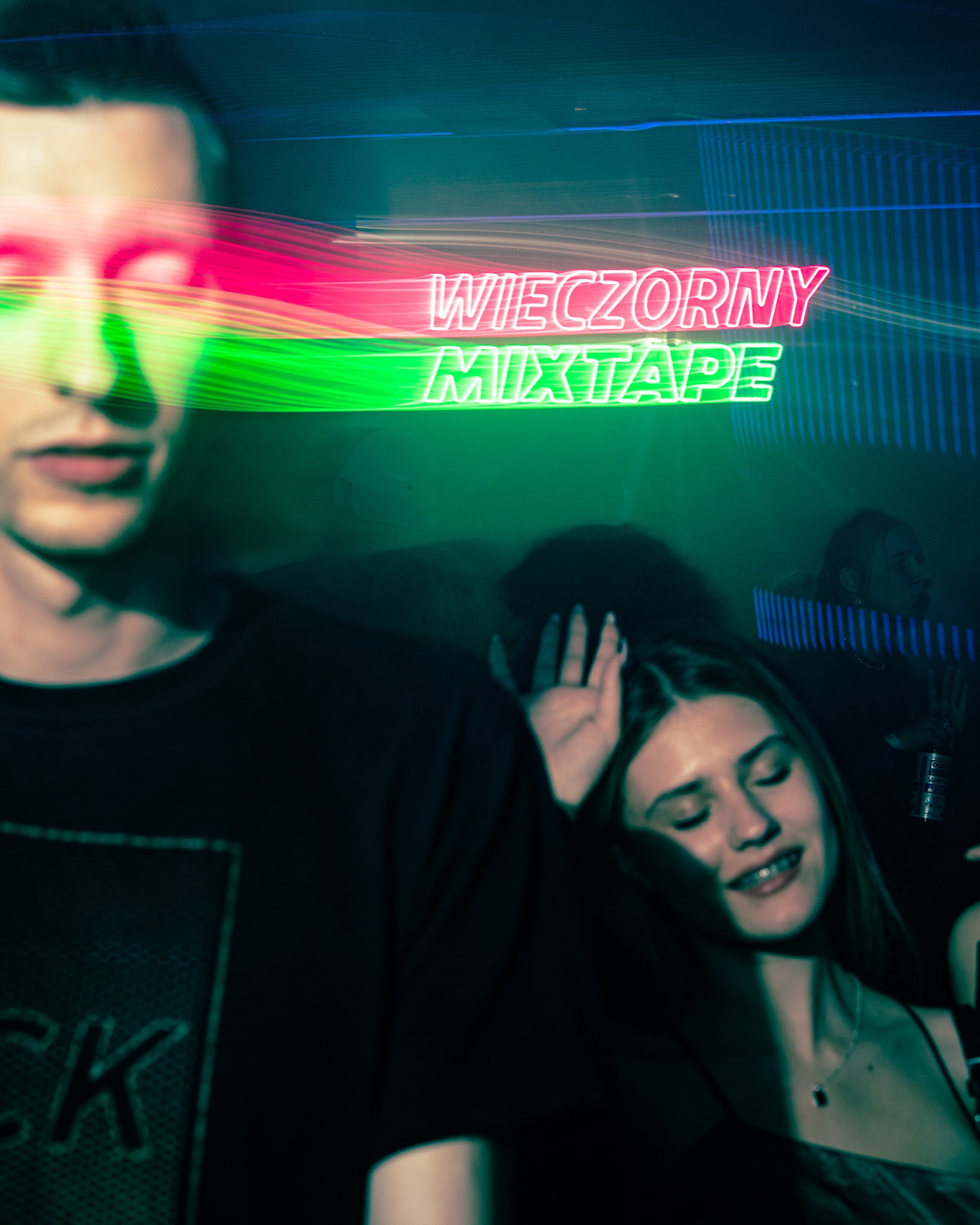 Młodzi ludzie w klubie nocnym, neonowy napis 'WIECZORNY MIXTAPE' w tle, dynamiczne ujęcie z rozmytymi postaciami.